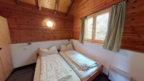 um pequeno quarto com uma cama e uma janela em Tschuggen 58 em Blatten bei Naters