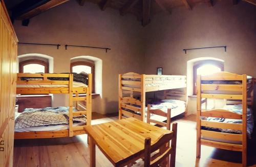 a room with four bunk beds and a wooden table at Forte di Machaby in Arnad