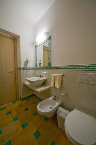a bathroom with a sink and a toilet and a mirror at Hotel Villa Fanusa in Siracusa