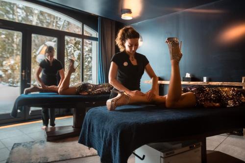 a woman sitting on a bed with her legs up at La Folie Douce Hotels Chamonix in Chamonix