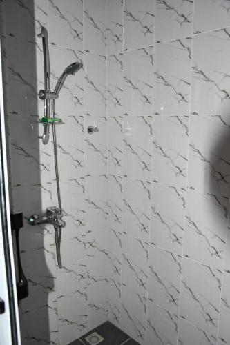 a shower in a bathroom with white marble tiles at Santa Monica Home Lodge in Senchi