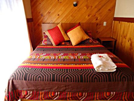 a bed with a colorful blanket and a towel on it at Boomerang Inn in Pucón