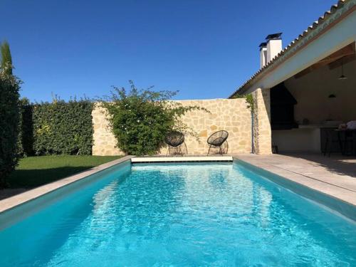 a swimming pool with two chairs next to a house at Modern villa with private pool in Malauc n in Malaucène