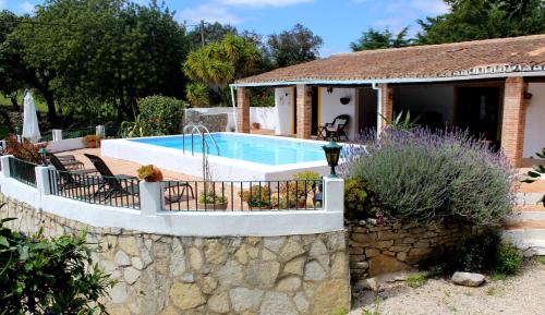a swimming pool in a garden with a house at La Quinta casa com piscina privada in Loulé
