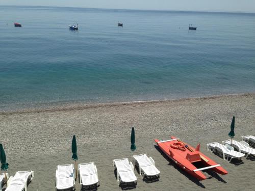 a group of chairs and a boat on a beach at Hotel Kennedy in SantʼAlessio Siculo