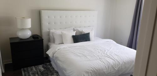 1 cama con sábanas y almohadas blancas y lámpara en Prime Location 1-Bedroom with Balcony and Pool en Los Ángeles