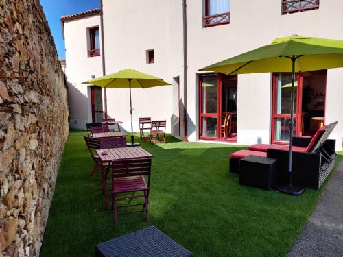 a group of chairs and tables with umbrellas at Hotel La Bosselle in Saint-Philbert-de-Grand-Lieu