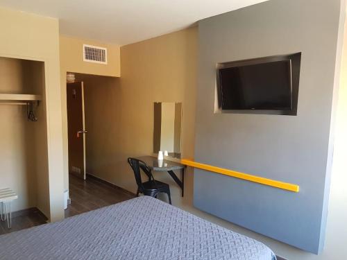 um quarto com uma cama e uma televisão na parede em Hotel Olivia em Nogales