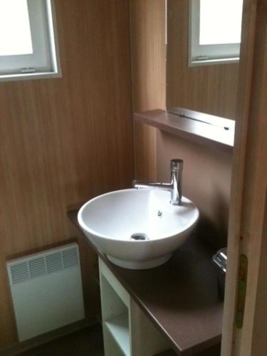 a bathroom with a white sink and two windows at BOURGUETTE La petite maison dans la prairie in Saint-Paul-Lizonne