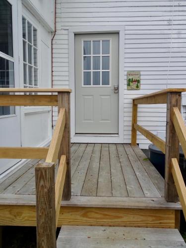 a wooden porch with a white door on a house at Craftsbury Farmhouse in Craftsbury