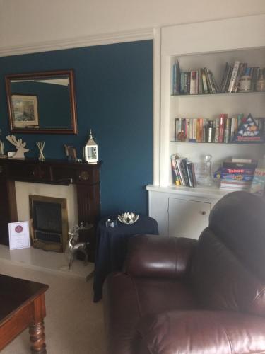 Arisaig Guest House في بيرث: غرفة معيشة مع أريكة ومدفأة