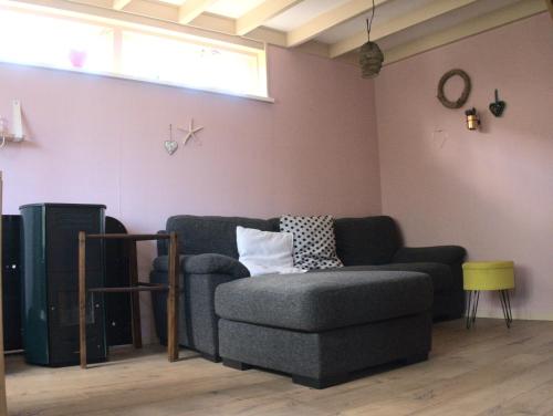 a living room with a couch and a chair at Small, cute and cozy little holiday home in Hippolytushoef