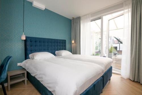 ein Schlafzimmer mit einem großen Bett und einer blauen Wand in der Unterkunft Hotel Royal in Noordwijk