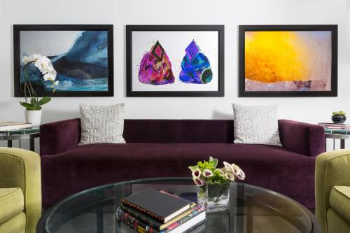 a living room with a purple couch and paintings at Studio Allston Hotel Boston in Boston
