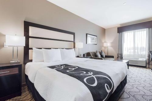 a hotel room with a large bed and a chair at La Quinta by Wyndham Auburn in Auburn