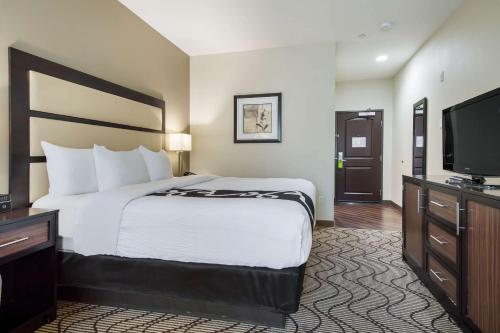 a hotel room with a bed and a flat screen tv at La Quinta by Wyndham Auburn in Auburn