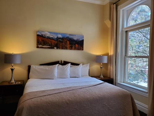 a bedroom with a large bed with two windows at Hotel Ouray - for 12 years old and over in Ouray