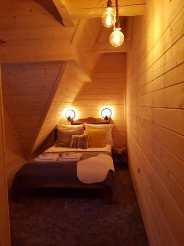 1 dormitorio con 1 cama en una cabaña de madera en Śwarny Domek, en Małe Ciche