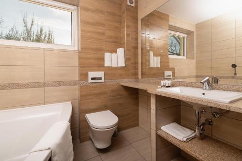 een badkamer met een toilet, een wastafel en een bad bij Hotel Olesno in Olesno