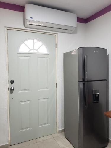 a kitchen with a refrigerator and a white door at Casa Zac Nicte Mx-Estudio SISAL in Cancún