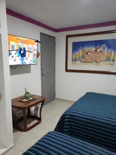 Habitación con cama, mesa y TV. en Casa Zac Nicte Mx-Estudio SISAL, en Cancún