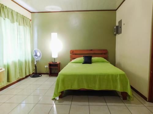 una camera con letto verde e lampada di Hotel Amjeco a San Isidro de El General