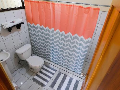 y baño con aseo y cortina de ducha. en Hotel Amjeco, en San Isidro