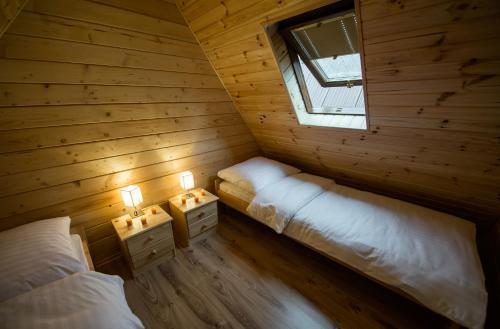 two beds in a wooden room with a window at Ross-domki in Sarbinowo