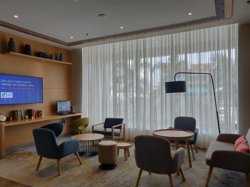a waiting room with tables and chairs and a tv at Holiday Inn Express Chennai OMR Thoraipakkam by IHG in Chennai