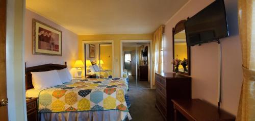 a bedroom with a bed and a flat screen tv at Pinebrook Motel in Lake George