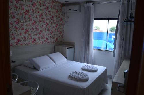 a small bed in a room with a window at Hotel Universo in Vitória da Conquista