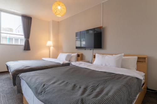 two beds in a hotel room with a flat screen tv at SUNDAY peace room 猿猴橋 #27 in Hiroshima