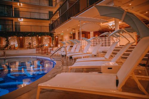 a pool with white lounge chairs next to a swimming pool at The Surfjack Hotel & Swim Club in Honolulu