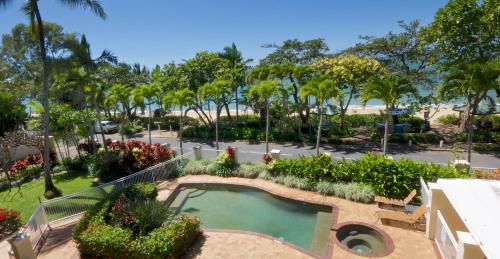 a large garden with a pool and trees at On The Beach in Trinity Beach