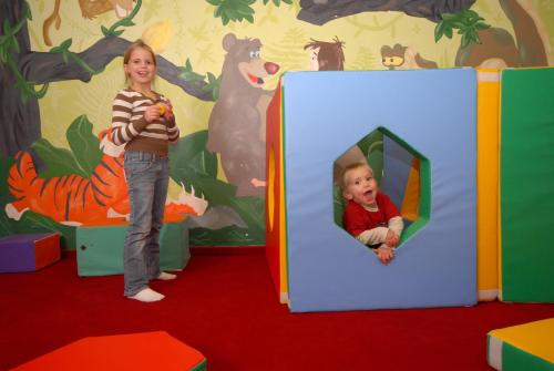 a young girl is standing in a play room with a mirror at Urlaubsland Sonnfeld in Flachau