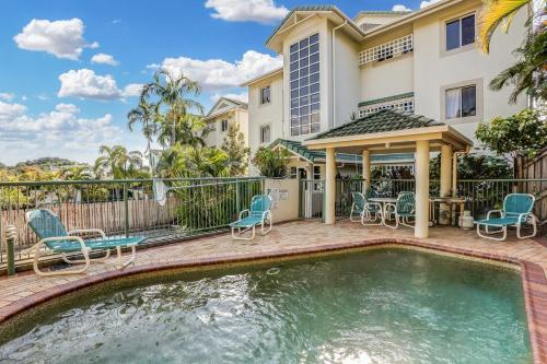 a house with a swimming pool with chairs and a gazebo at On The Beach Apartments in Trinity Beach