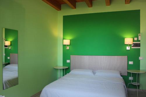 1 dormitorio verde con 1 cama y 2 mesas en B&B Ai Prati, en Lesignana