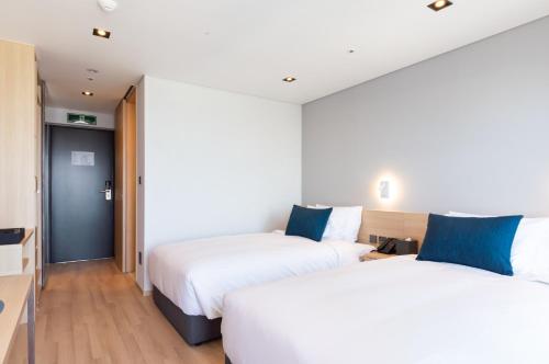 a hotel room with two beds and a hallway at Connect Busan Hotel & Residence in Busan