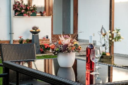 una mesa con un jarrón de flores y una copa de vino en Gästehaus Ranftl en Unterlamm