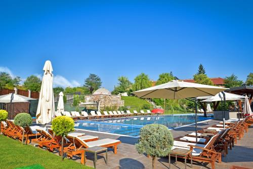 a pool with a bunch of chairs and umbrellas at Regnum Bansko Ski Hotel & SPA in Bansko