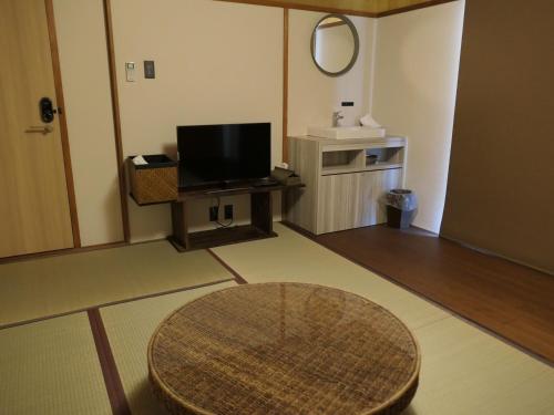 a living room with a table and a television at Share Hotel 198 Beppu in Beppu