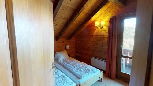 1 dormitorio con 1 cama en una cabaña de madera en Tschuggen 24 en Blatten bei Naters