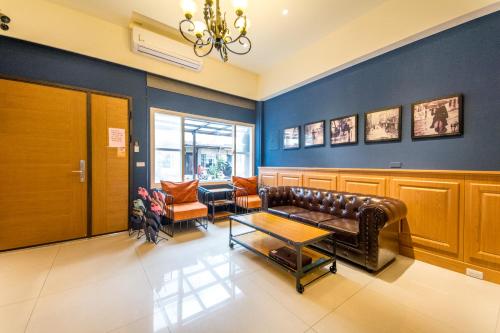 a waiting room with a leather couch and chairs at Alan's House B&B in Jiaoxi