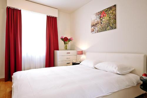a bedroom with a white bed with red curtains at CITY STAY - Forchstrasse in Zürich