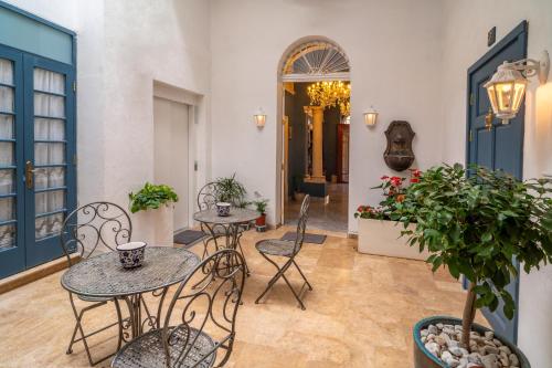 a patio with two tables and chairs and plants at Julina Boutique Living in Mosta