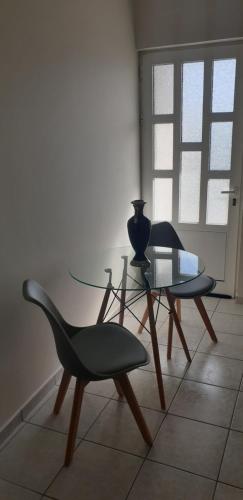 two chairs and a glass table in a room at Alexia's Apartments in Rio