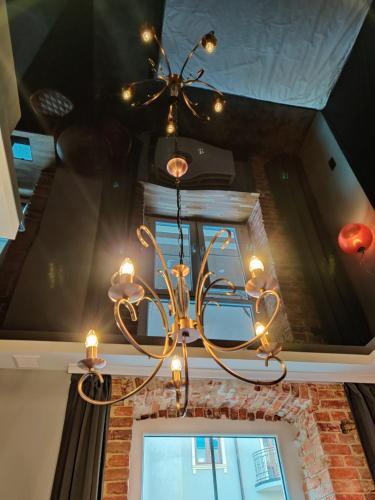a chandelier hanging from a ceiling with a window at Piotrkowska.eu Apartament Romantica in Łódź