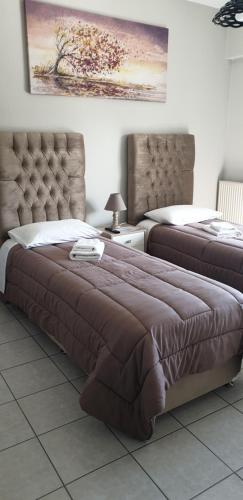 a bedroom with two beds with a large bedspread and a headboard at Alexia's Apartments in Rio