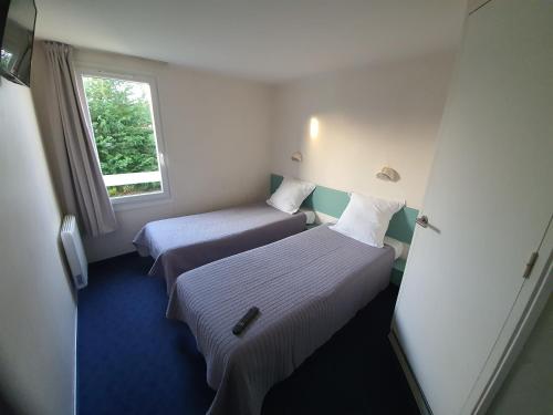 a hotel room with two beds and a window at Le 81 HOTEL in Castres