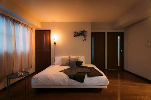 a bedroom with a bed with white sheets and pillows at gate nagasaki stay&green in Nagasaki